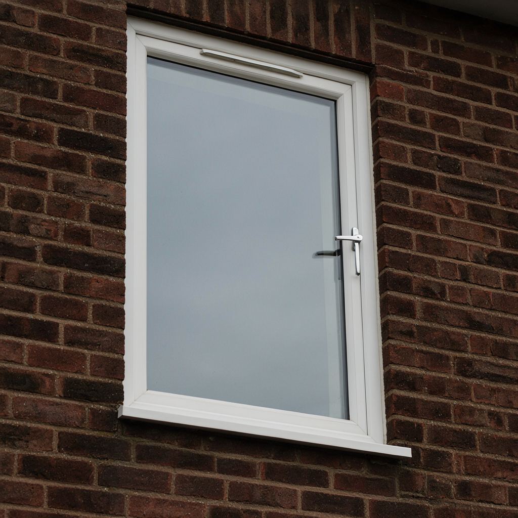 Detail van een antraciet kunststof raamkozijn met een moderne deurkruk op een houten achtergevel in Bathmen