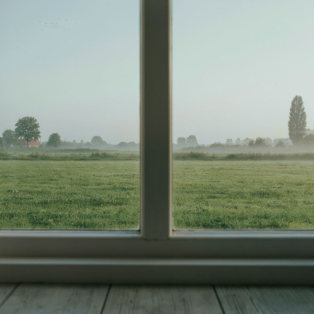 Licht landelijk interieur in Markelo met zicht door kunststof schuifraam op een ruime boerentuin